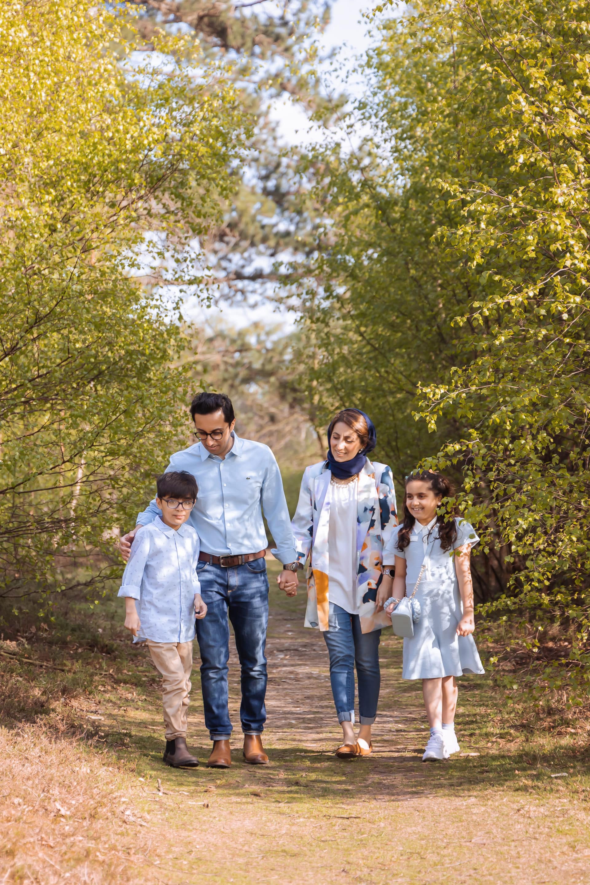 outdoor photograph, family walking through the park surrounded by trees.  family all talking.  Taken by family photographer sutton coldfield birmingham