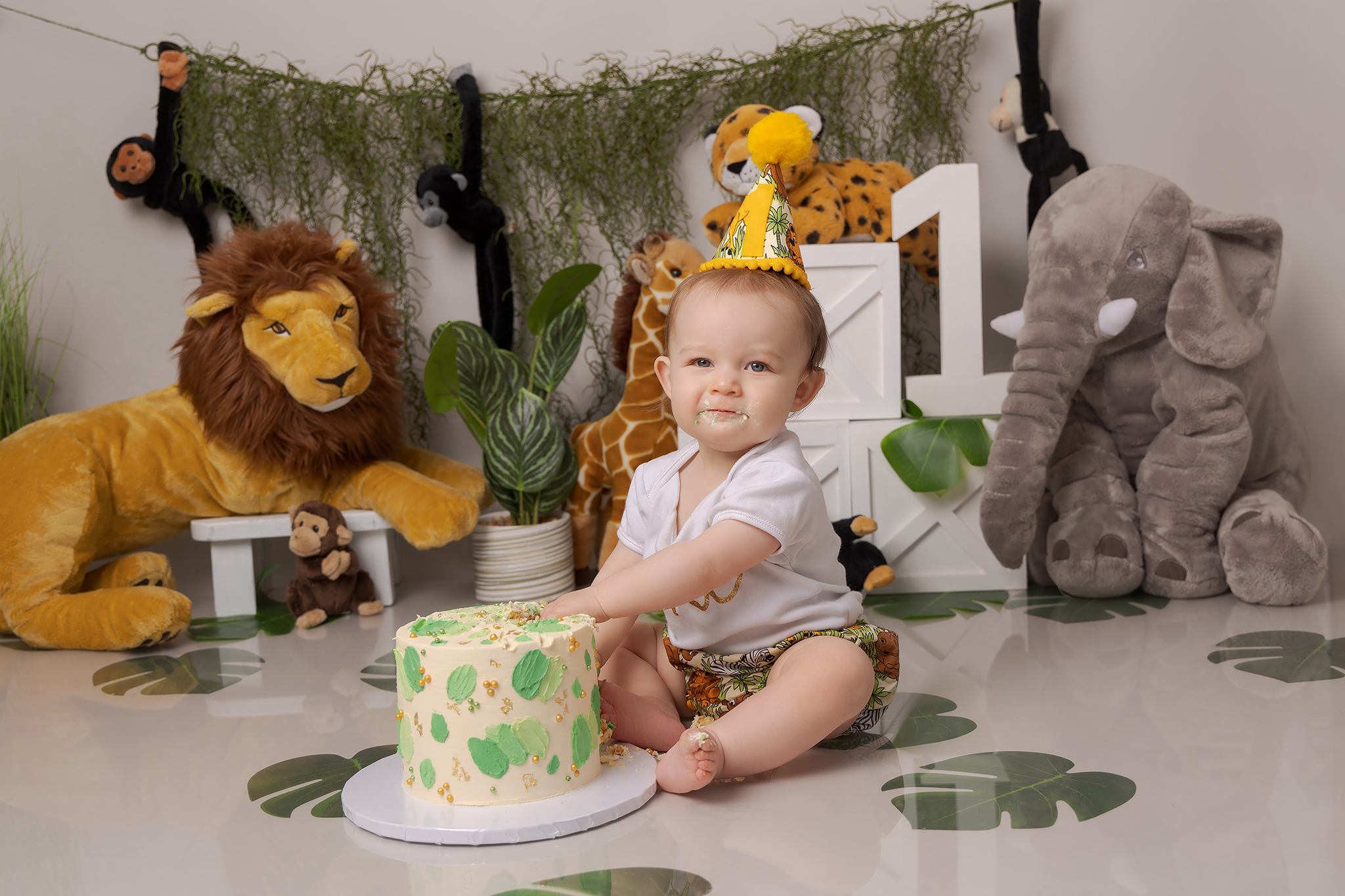 One year old with a jungle themed cake smash set about to break open into her cake
