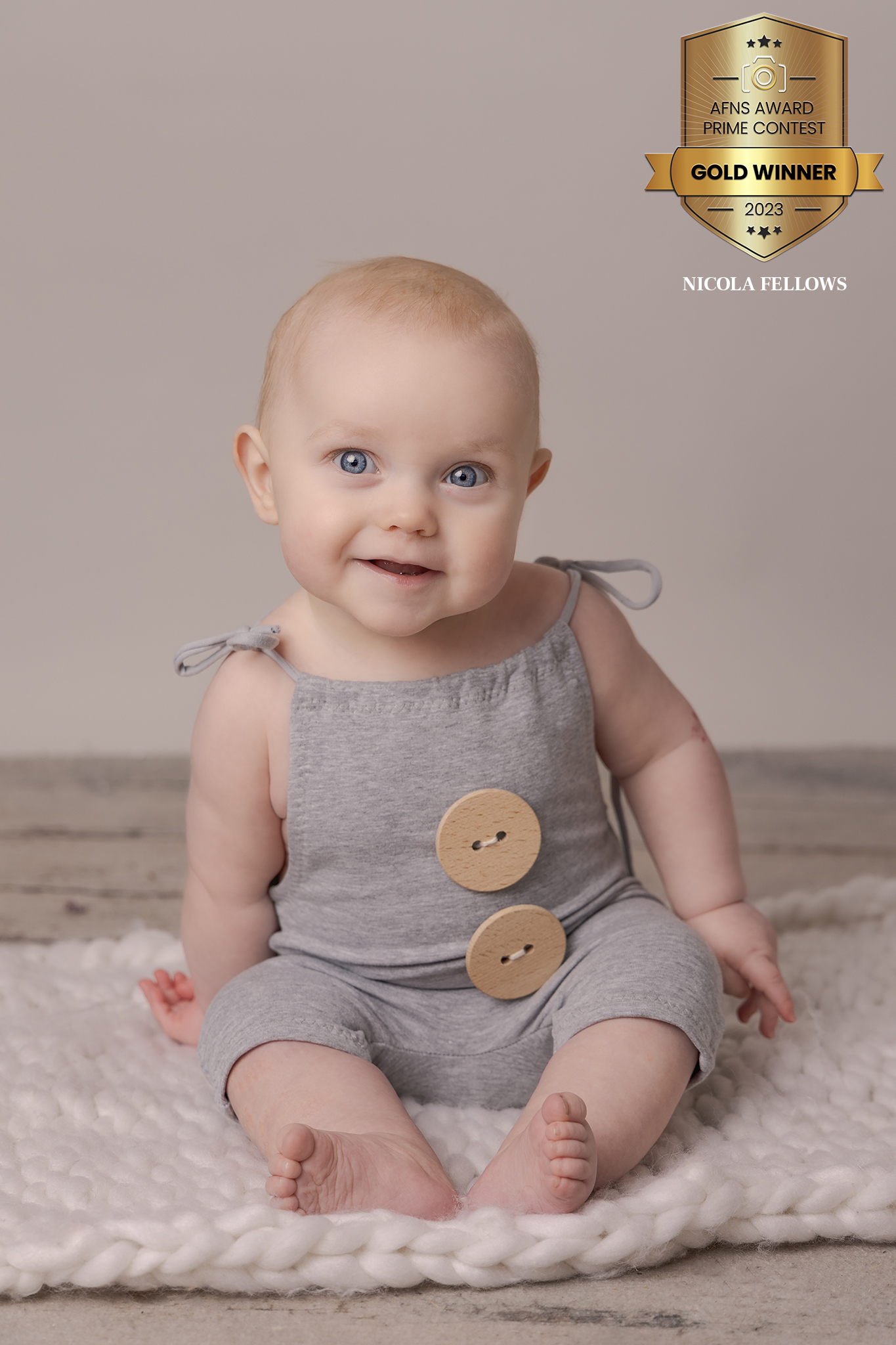 little sitter wearing grey on white wooden floor, taken by baby photographer Sutton Coldfield birmingham
