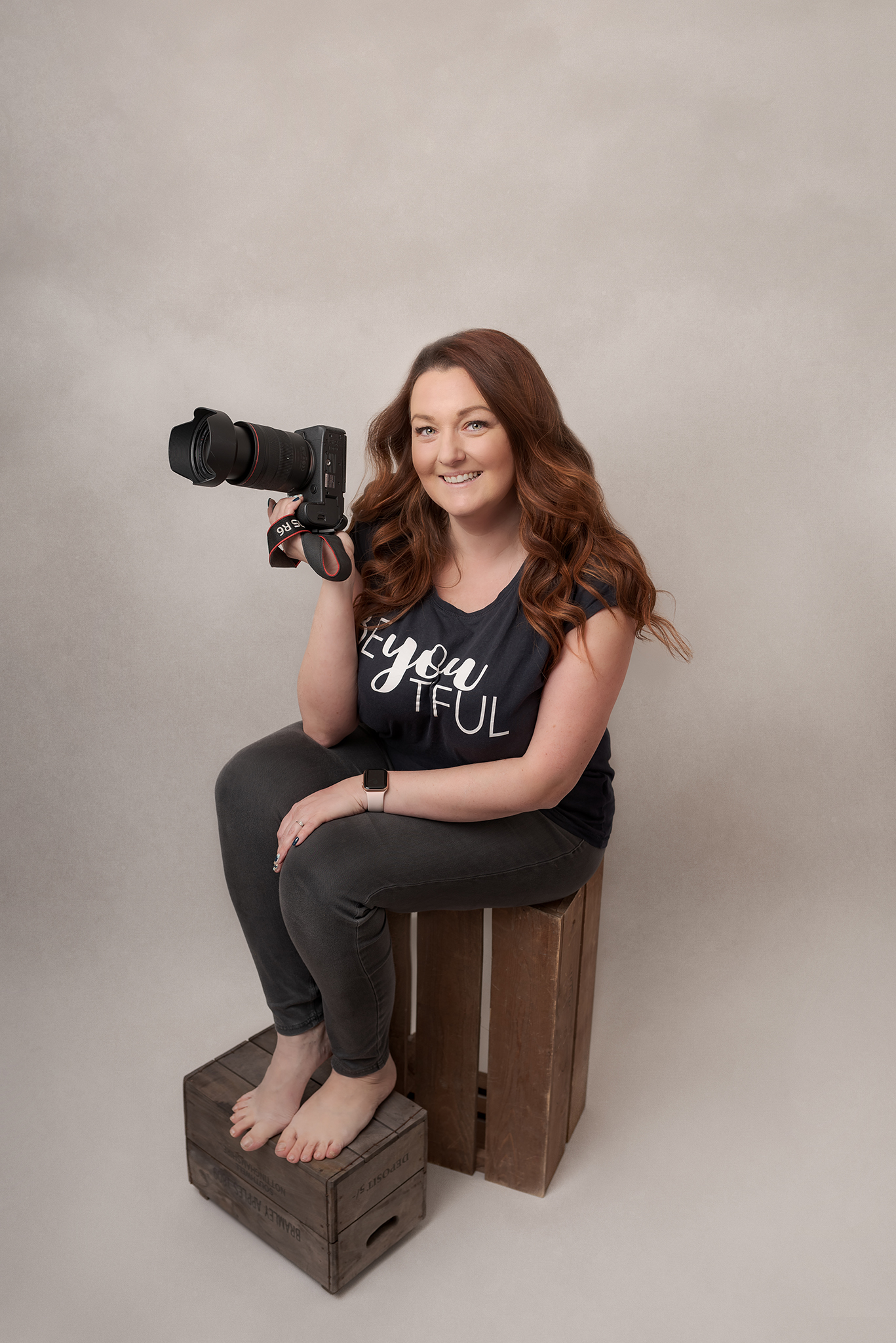 Photographer from Sutton Coldfield birmingham sat on a brown box holding her camera